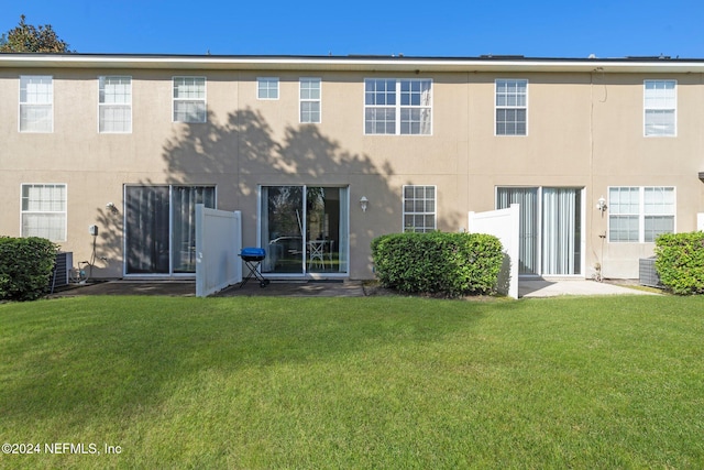 back of house with central AC unit and a lawn