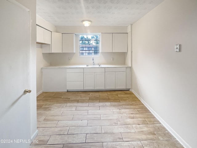 kitchen featuring white cabinetry, a textured ceiling, and sink