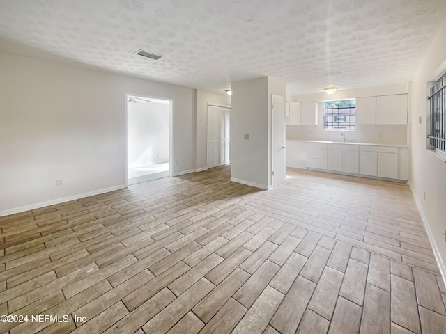 empty room featuring light hardwood / wood-style floors, a textured ceiling, and sink