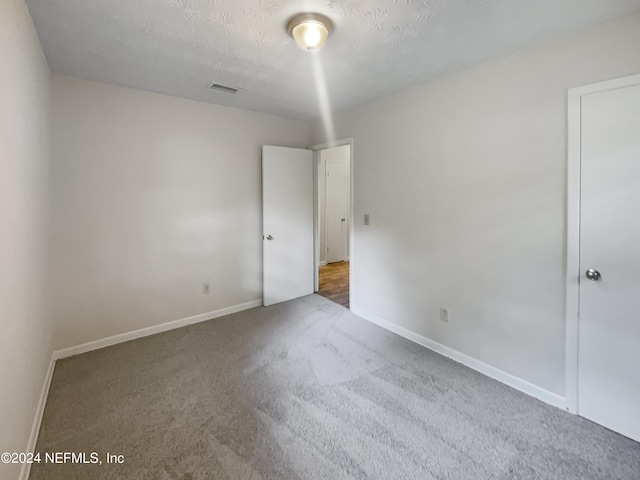 carpeted empty room with a textured ceiling