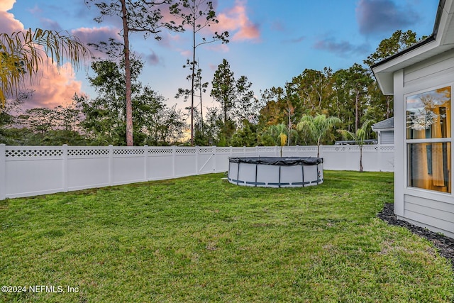 yard at dusk featuring a covered pool