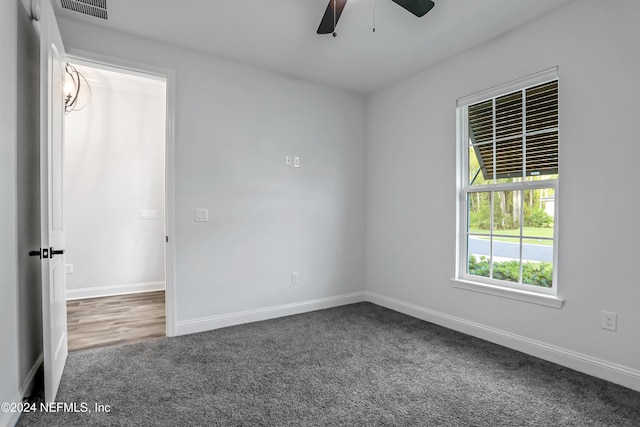 empty room with dark colored carpet and ceiling fan