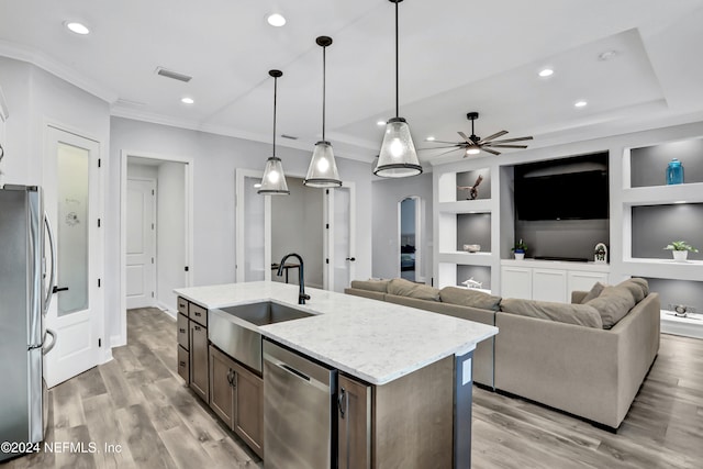 kitchen with light hardwood / wood-style floors, sink, an island with sink, appliances with stainless steel finishes, and decorative light fixtures