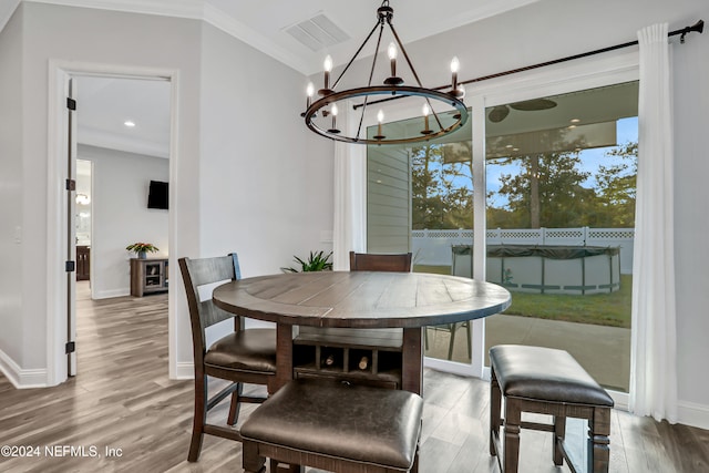 dining space featuring an inviting chandelier, wood-type flooring, and crown molding