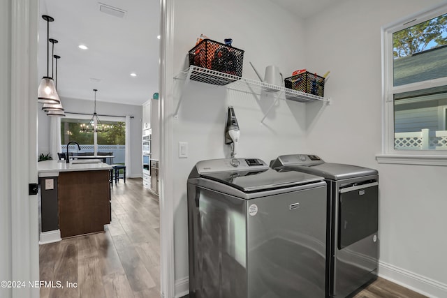 clothes washing area featuring hardwood / wood-style floors, a wealth of natural light, and washing machine and dryer