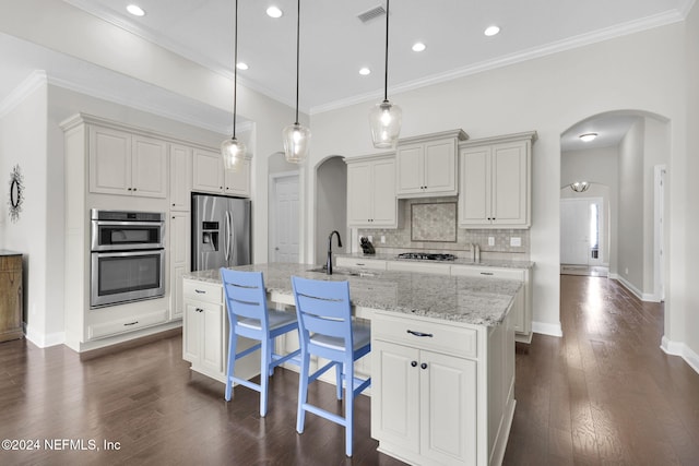 kitchen featuring sink, appliances with stainless steel finishes, a kitchen island with sink, pendant lighting, and dark hardwood / wood-style flooring