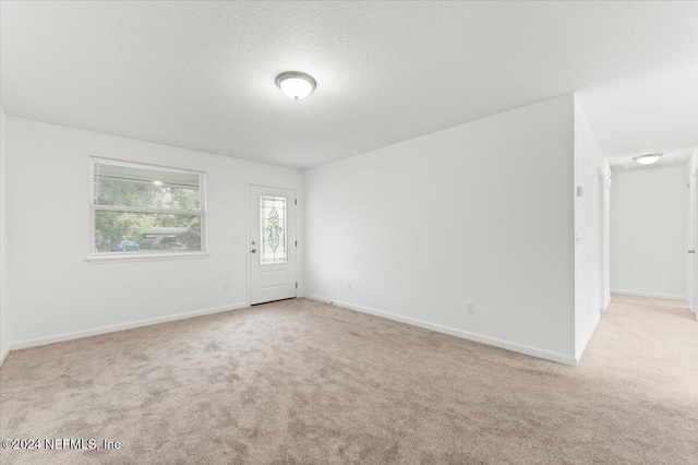 empty room with a textured ceiling and light carpet