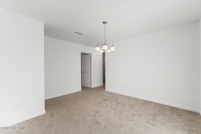 carpeted spare room with a chandelier