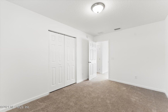 unfurnished bedroom with a closet, carpet, and a textured ceiling