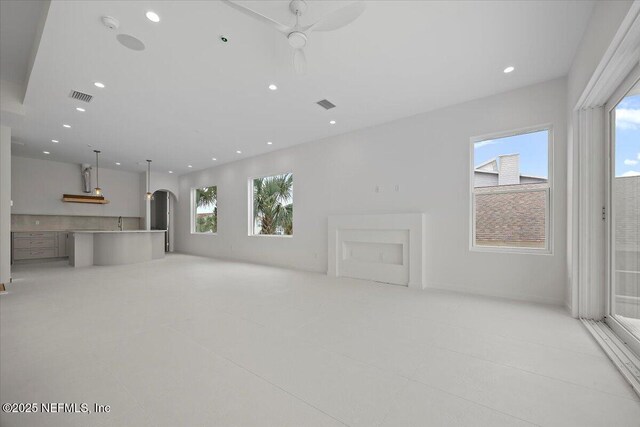 unfurnished living room with ceiling fan, light tile patterned floors, and a healthy amount of sunlight