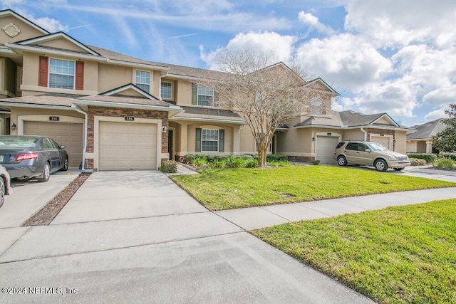 townhome / multi-family property with a front lawn and a garage