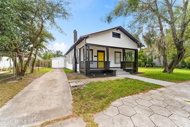 bungalow featuring a front lawn, a shed, and covered porch