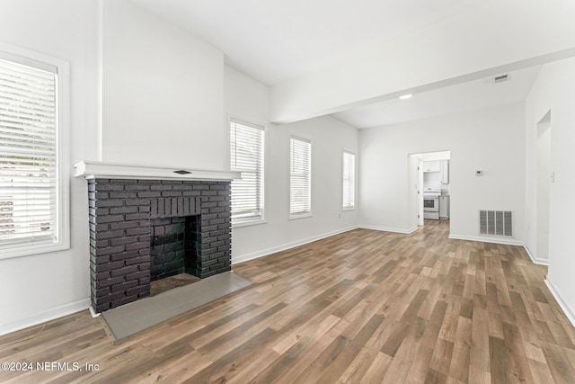 unfurnished living room with a brick fireplace and hardwood / wood-style flooring