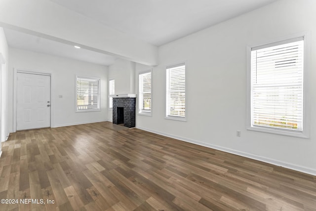 unfurnished living room with a fireplace, dark hardwood / wood-style floors, and plenty of natural light