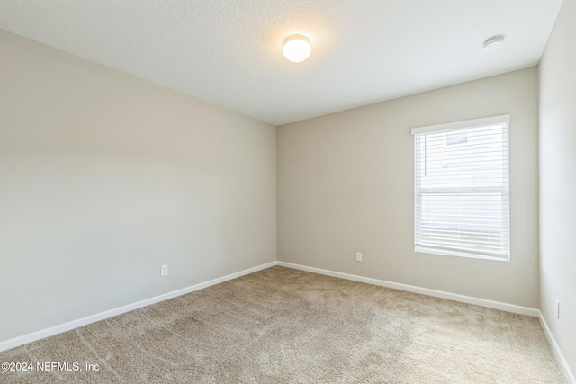 carpeted empty room with a textured ceiling