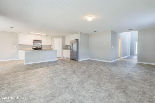 interior space with appliances with stainless steel finishes, open floor plan, visible vents, and white cabinets