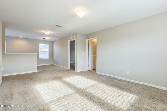 spare room with carpet flooring, visible vents, and baseboards