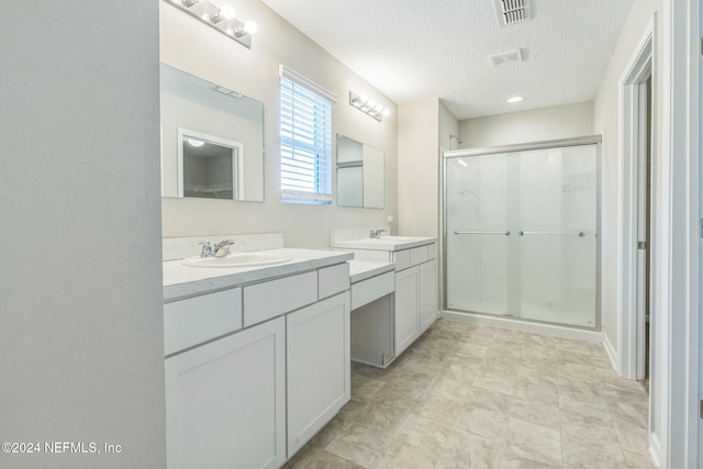 bathroom featuring vanity, a shower with door, and a textured ceiling