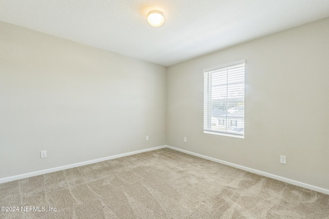 carpeted spare room with baseboards and a textured ceiling