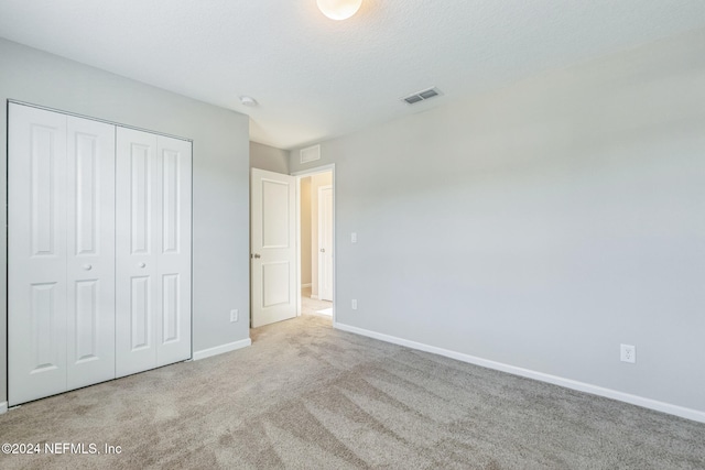 unfurnished bedroom featuring carpet floors, baseboards, visible vents, and a closet