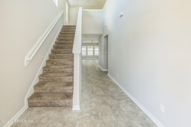 stairway featuring a high ceiling and baseboards