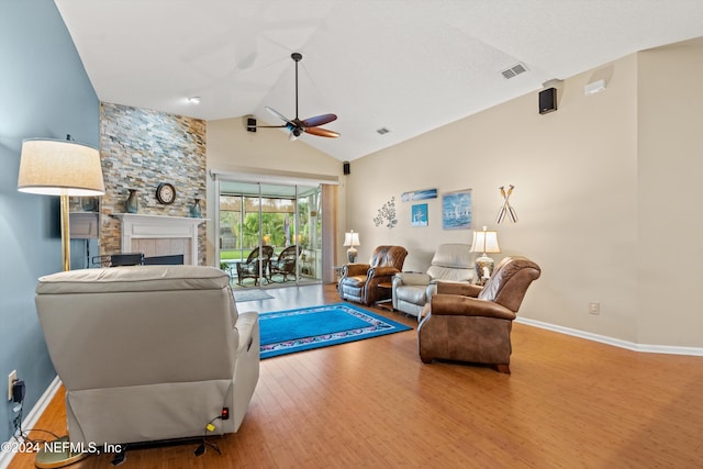 living room with hardwood / wood-style floors, ceiling fan, high vaulted ceiling, and a tile fireplace