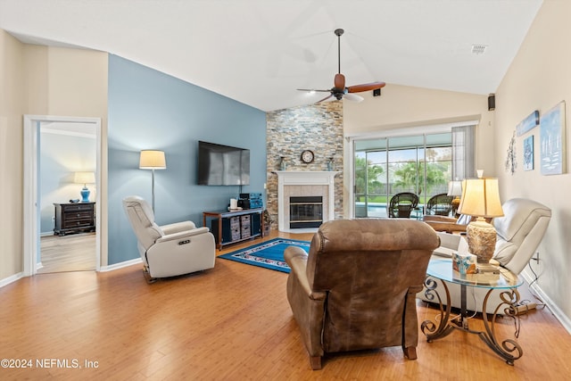 living room with a fireplace, ceiling fan, light hardwood / wood-style flooring, and vaulted ceiling