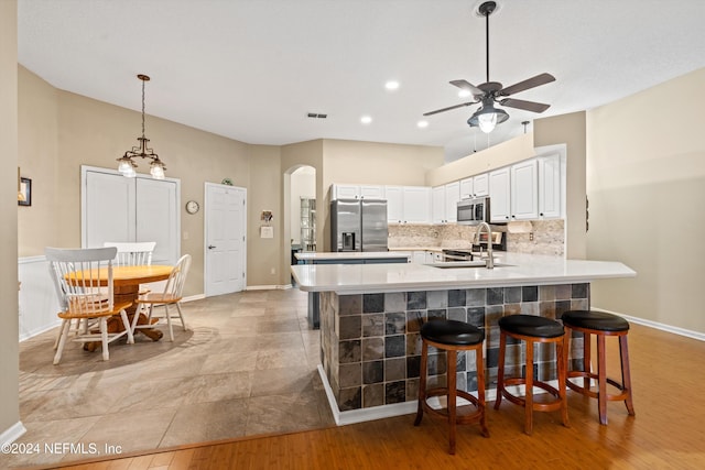 kitchen with stainless steel appliances, ceiling fan, light hardwood / wood-style flooring, white cabinets, and decorative backsplash