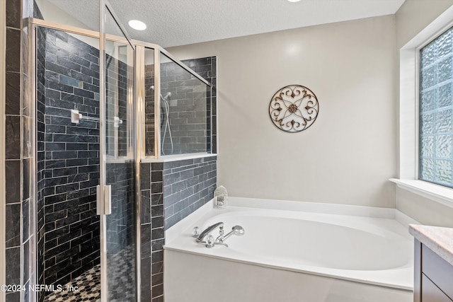 bathroom featuring independent shower and bath, vanity, and a textured ceiling