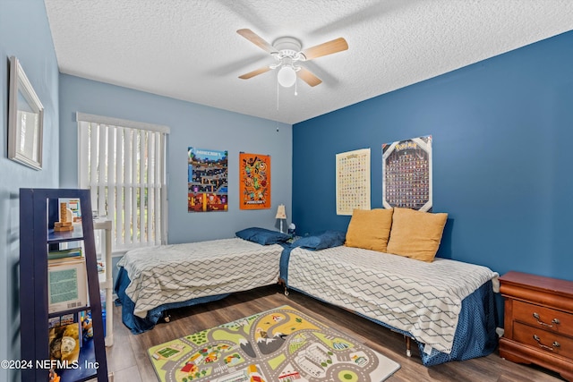 bedroom with hardwood / wood-style floors, ceiling fan, and a textured ceiling