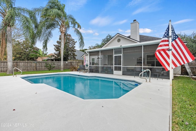 view of swimming pool with a sunroom and a patio area