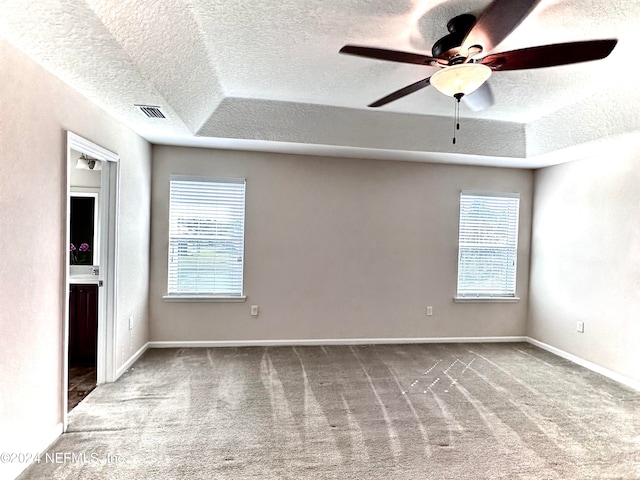 unfurnished room with carpet, a textured ceiling, ceiling fan, and a tray ceiling