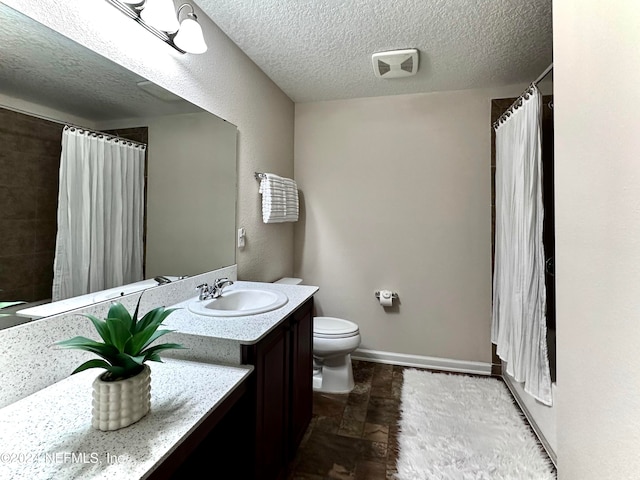 bathroom featuring vanity, a textured ceiling, and toilet