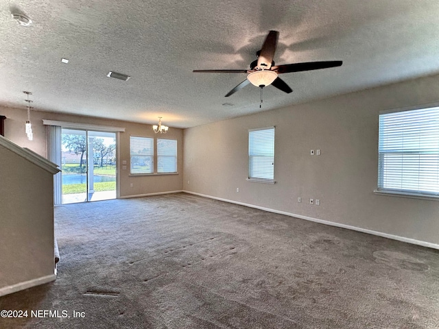 unfurnished living room featuring ceiling fan with notable chandelier, a textured ceiling, and dark colored carpet