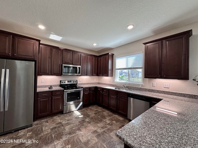 kitchen featuring appliances with stainless steel finishes, sink, a textured ceiling, and dark brown cabinetry