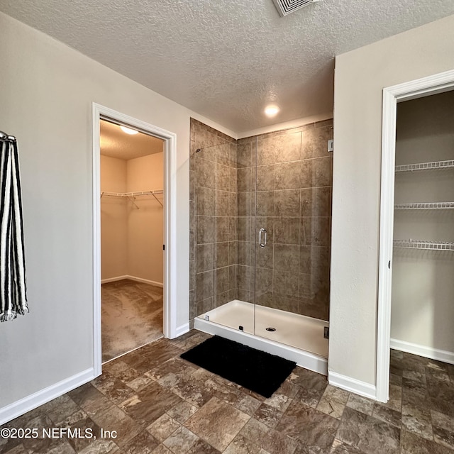 bathroom with a shower with door and a textured ceiling