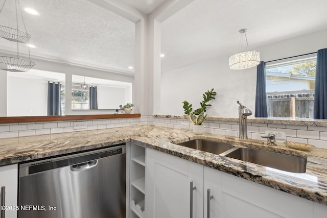 kitchen featuring pendant lighting, dishwasher, sink, a wealth of natural light, and white cabinetry