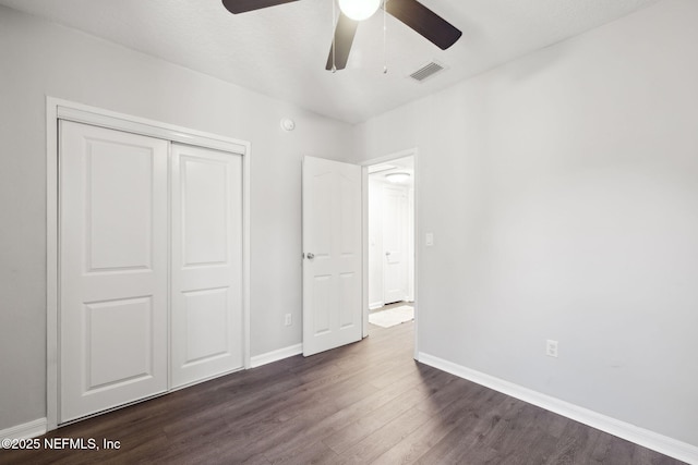 unfurnished bedroom featuring a closet, ceiling fan, and dark wood-type flooring