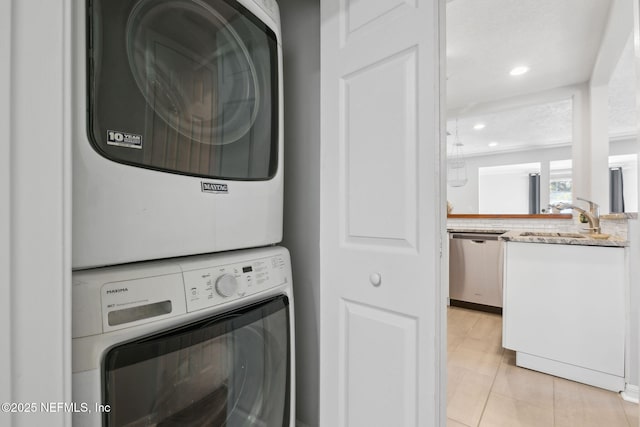 laundry area with light tile patterned flooring, sink, and stacked washer / dryer