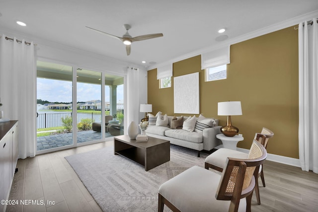 living room with light wood-type flooring, ceiling fan, a water view, and ornamental molding