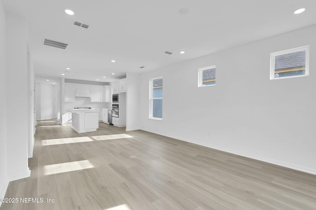 unfurnished living room featuring baseboards, light wood-style flooring, visible vents, and recessed lighting