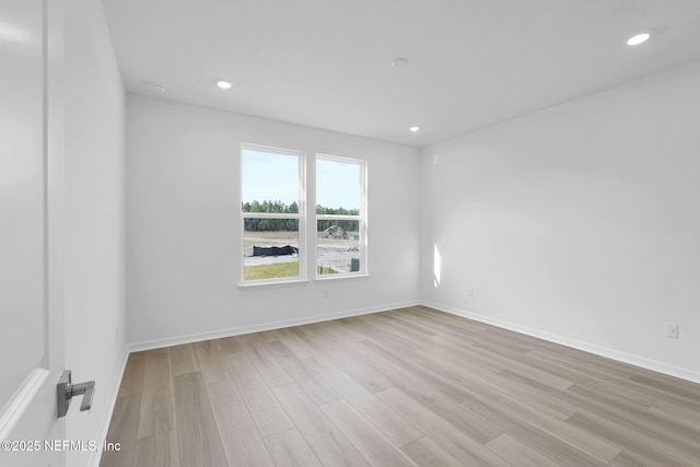 empty room with light wood-type flooring, baseboards, and recessed lighting