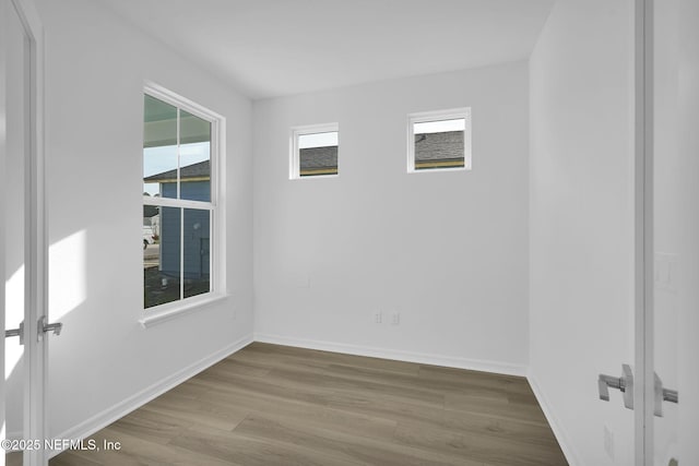 empty room featuring baseboards, wood finished floors, and french doors