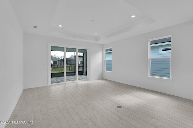 spare room with light wood-style floors, a tray ceiling, and recessed lighting