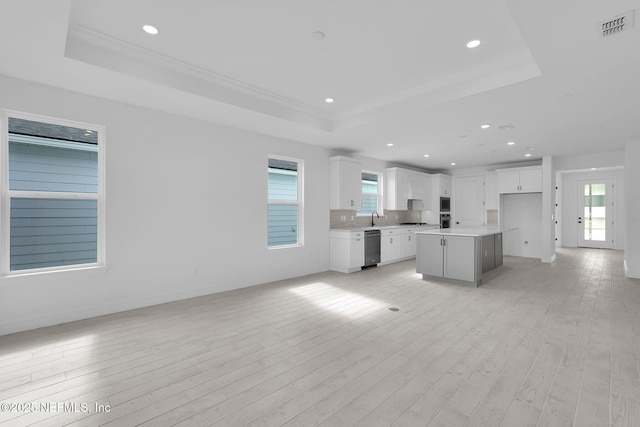 kitchen featuring light wood-type flooring, a raised ceiling, visible vents, and open floor plan