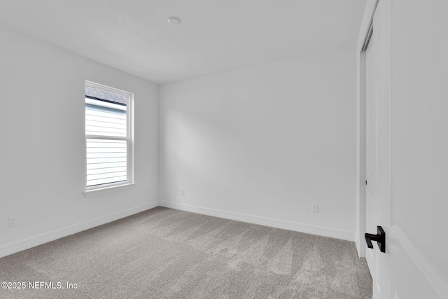 carpeted spare room featuring baseboards