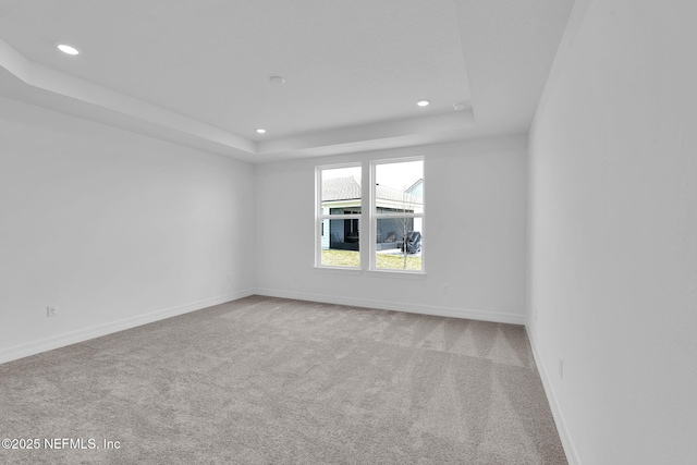 empty room with recessed lighting, carpet flooring, a raised ceiling, and baseboards