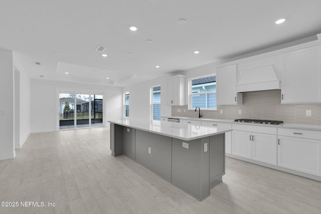 kitchen with decorative backsplash, a center island, custom exhaust hood, and gas cooktop