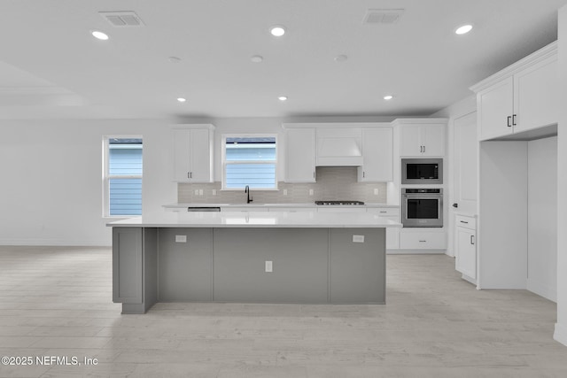 kitchen with a kitchen island, a sink, visible vents, appliances with stainless steel finishes, and tasteful backsplash