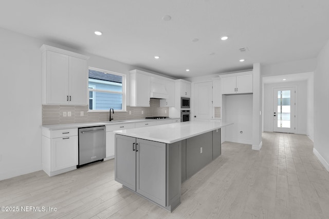 kitchen featuring appliances with stainless steel finishes, decorative backsplash, white cabinetry, and light wood-style floors